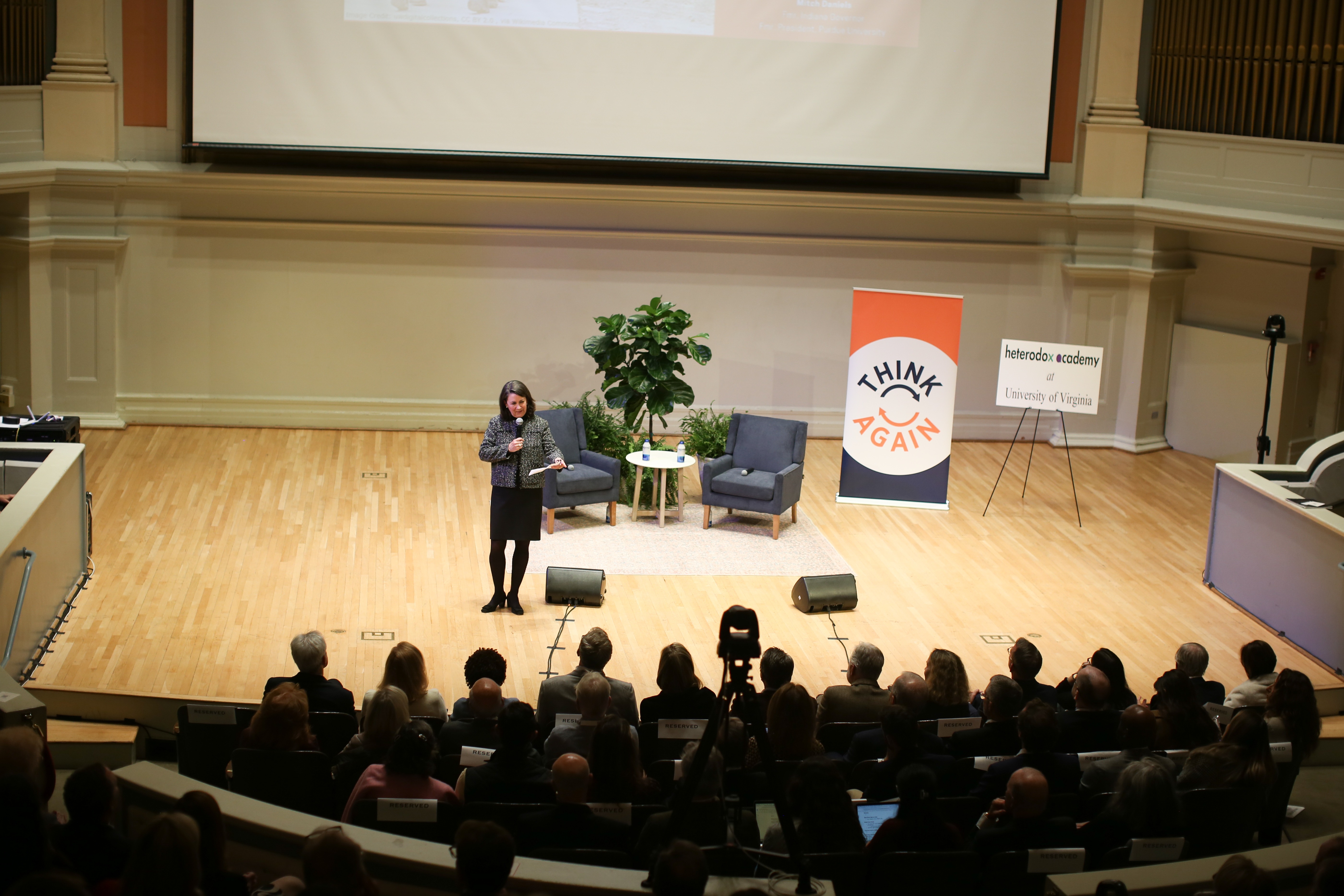 Speaker presenting to academic audience with Think Again and Heterodox Academy banners