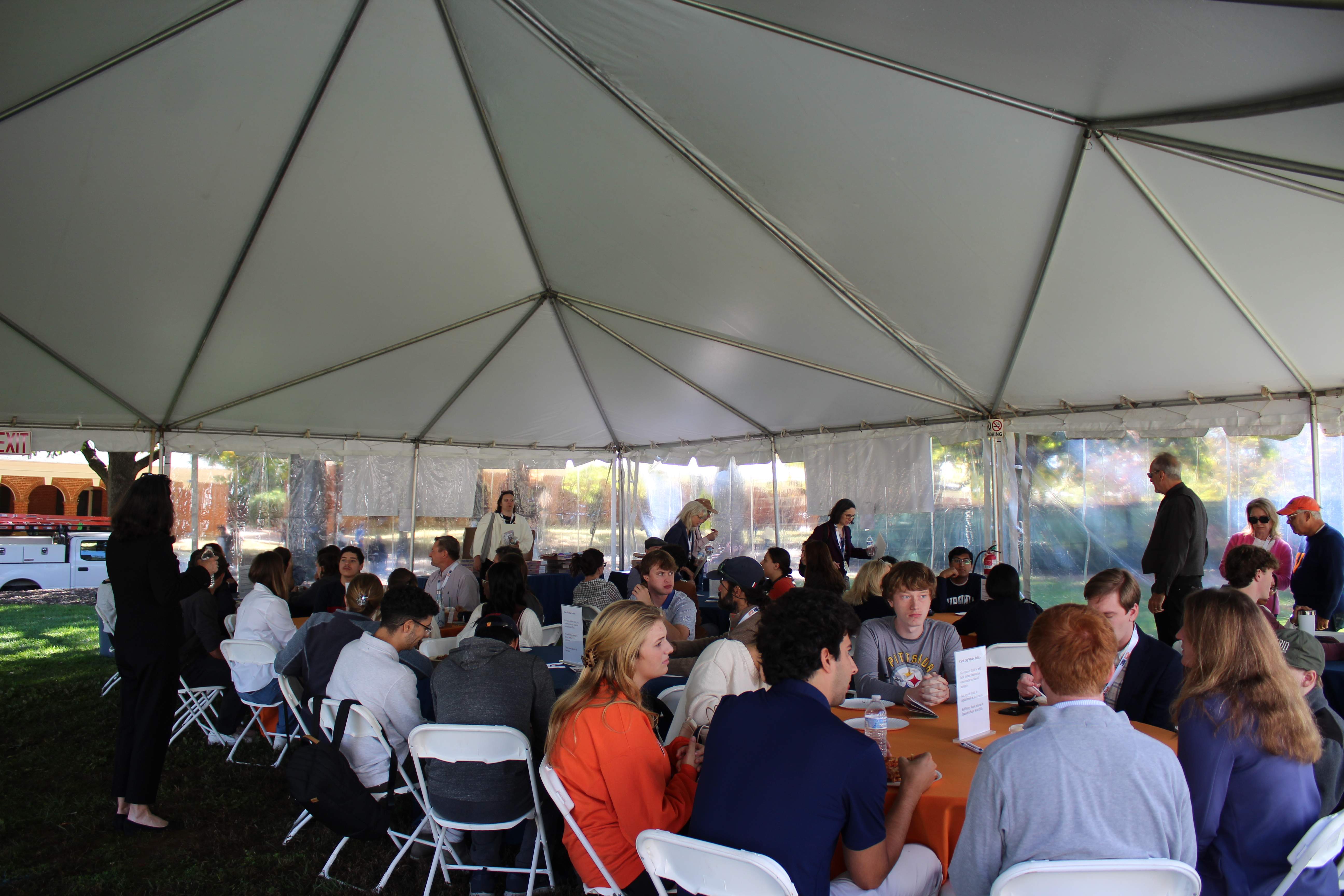Large outdoor tent event with participants at tables